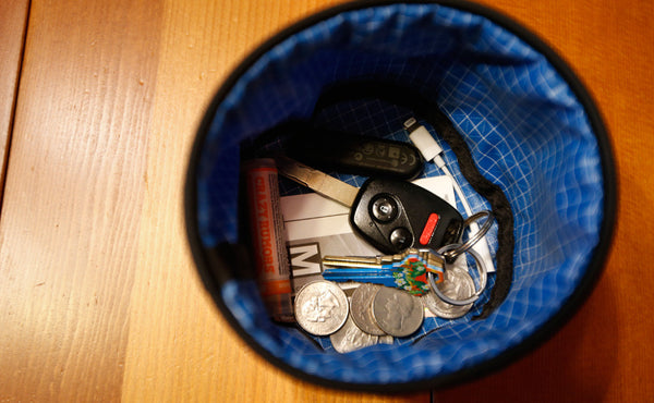 A Small Travel Tray holding some change, a keydrive, a dongle, a Metrocard, chapstick, and a pair of keys.
